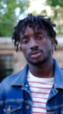 Afrikalı genç adam, olumsuz durumu reflekslerle ifade ederek parmağını aşağı doğru göstererek onaylamadığını gösteriyor.