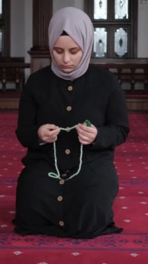 Camide yerde dua eden tesettürlü genç bir kadın, elinde tespihle dua eden bir kadın, caminin içinde dua eden Müslüman sözleşmesine tapan bir kadın.