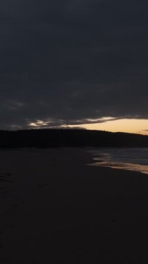 Bulutlu günbatımında şehrin koşuşturmasından kaçan adam plajda spor yapıyor.