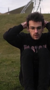 Genç adam yeşil çimlerde şınav çekiyor, adam parkta spor yapıyor, yaz tatili vücudunu geliştirmek için parkta spor yapıyor.