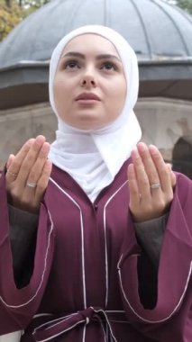 Asyalı Müslüman Dilek Duası, cami avlusunda dua eden beyaz bir kızın görüntüsü, açık havada İslami ibadet, çarşaf kültür avlusu
