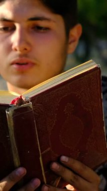 Genç adam açık havada Kuran okuyor, Kuran okuyor, açık havada kitap okuyor, doğa bahçesinde ibadet ediyor.