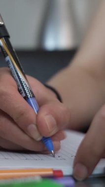 Öğrencinin renkli kalemlerle notlar aldığını, mavi kalemle deftere yazdığını, kalemle yazdığını yakın plan görüntüsü