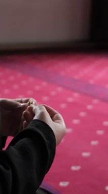 Müslüman bir kadın elleriyle namaz kılıyor, tesettürlü bir kadın camide dizleri üzerine çöküp dhikr okuyor.