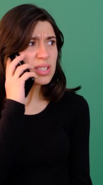 Yeşil ekranda konuşan bir kadın, mutsuz ve kızgın beyaz bir kadın. Krom anahtarın önünde telefonla konuşan, izole edilmiş yeşil arka plan.