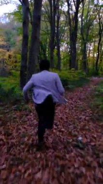 Ormanın ortasında koşan bir adam, etrafına bakar ve kaybolduğunu anlar, genç kahverengi yaprak yolda hızla yürür.