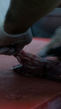 Şef çiğ eti bıçakla kesiyor, usta şefin yakın plan görüntüsü bıçakla biftek keserken, et doğrarken, biftek keserken, kırmızı arka planda dana eti keserken.