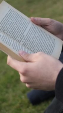 Çimenler üzerinde kitap okuyan, güneşli bir günde çimlerin üzerinde roman okuyan, güneşli bir günde parkta boş vakit geçiren yalnız bir adamın görüntüsü.