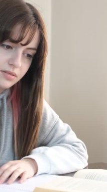 Masada ders çalışan, kalemle not alan, sınavlarına hazırlanan genç bir kız resmi.