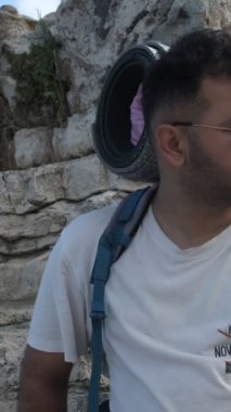 Backpacker camper boy, young male resting with camping gear in backpack, view of camper wearing glasses viewing scenery, looking araound with camping gear