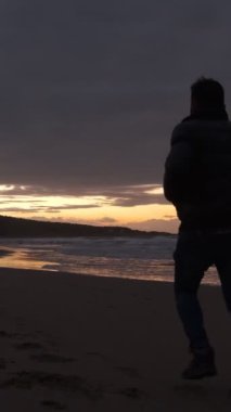 Deniz kenarında rahatlayan bir adam spor yaparak manzaraya karşı