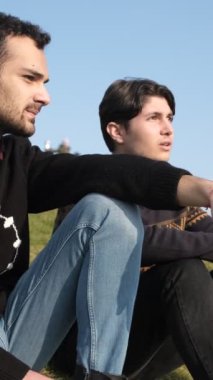 İki yakın arkadaş çimenlerde sohbet eder, güneşli bir günde parkta güneşlenir, palmiye ağaçları konseptiyle parkta dinlenir.