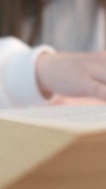 Romanın sayfalarını onun önünde çevirerek okumak, yakından bakmak, genç bir kızın kitap okuması, kitabın sayfalarını çevirmesi, başka bir sayfaya geçmesi.