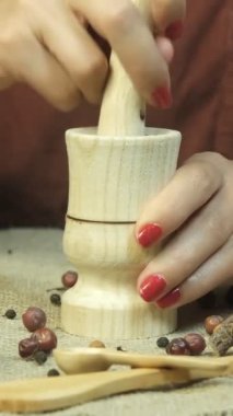 Female hand pounding the spices, image of woman hand beating spices in wooden pestle, crushing spices with nature theme, nature products theme indoors