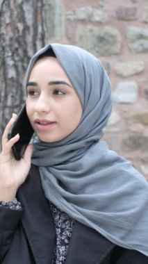 Müslüman bir kadın telefonla arıyor, telefonla iletişim kuruyor, dışarıda vakit geçiriyor, Müslüman bir kız teknoloji konuşuyor.