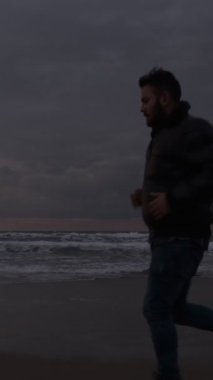 Spor yapan bir adamın, dalgalarla yarışır gibi, plajda rahatlama seansı yaparken görüntüsü.