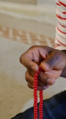 Afrikalı siyahi adamın elinde bir tespih vardır. Müslümanlar camide ilahi söylerken tespih çekerler. İslam dini kutsal bir dindir.