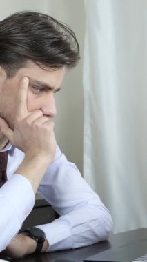 Ev ofisinde uzaktan çalışan genç bir adamın fazla mesai görüşü, evdeki masa başı işçisinin çalışma ortamı, beyaz arka planda bilgisayardan çalışan gömlekli bir çalışan.