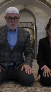 Camide dua eden büyükbaba ve torunun resmi, tarihi camide namaz kılan Müslümanların görüntüsü