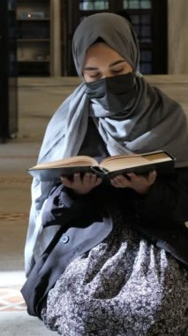 Genç Müslüman kadın, Maskeli Müslüman kadın Kuran okuyor, kadın İslam kurallarına tapıyor.