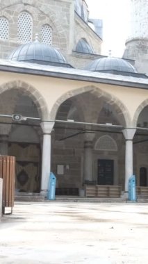 Yaşlı adam caminin avlusunda vakit geçiriyor. Yaşlı adam, taştan yapılmış tarihi caminin avlusunu ziyaret ediyor.