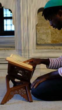 Camide Müslümanları okuyan Afrikalı bir adam, kafasında dini bir şapka olan adam,