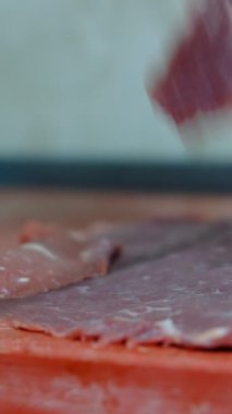 Şef çiğ eti bıçak videolarıyla keser, usta şefin bıçakla biftek keserken, et doğrarken, biftek keserken, kırmızı arka planda dana eti yerken yakın plan görüntüsü.