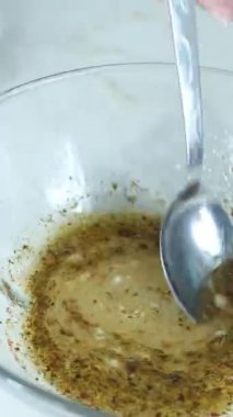 Cam kasede limon ve zeytinyağı kullanarak sos yapmak, beyaz arka planda karıştırarak sıvı sos hazırlamak, balık marine etmek için sos hazırlamak.