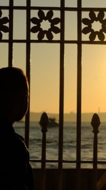 Günbatımında İstanbul Boğazı yakınlarındaki cami ile boğazı ayıran korkuluklardan gölgeler ve siluetler yaratıldı 