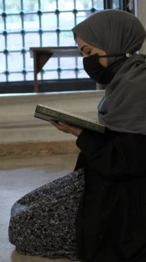 Genç tesettürlü kadın, genç kız diz çöküp Kuran okuyor, İslam kurallarına göre dua ediyor, tesettürlü kız caminin içinde dua ediyor.
