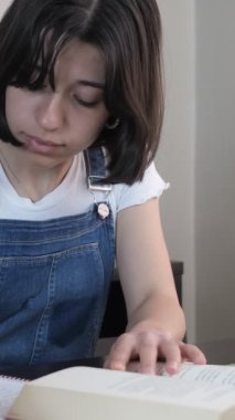 Önündeki kitaba göre not alan öğrenci, evde ders çalışan kız, defterine kitabın özetini yazan kız.