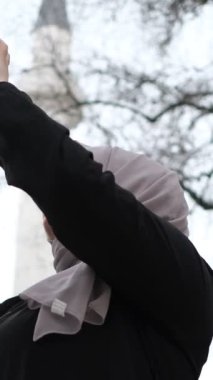 Telefonla tarihi eski caminin videosunu çeken tesettürlü kadın, tarihi açıdan önemli binaların fotoğraflarını çekiyor.