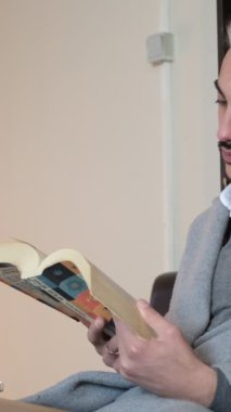 Genç adam içeride masasında kitap okuyor, yazılı belgeyi dikkatlice inceliyor, dudağıyla kitap okurken...