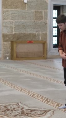 Genç Müslüman adam büyük caminin içinde ibadet eder, ibadet kurallarına göre secde eder, dini İslam 'a tapınma kurallarına göre yaşar