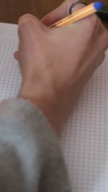 Evde okuyan genç bir erkek, sınavlara hazırlanma konsepti, elinde kalemle not defteri tutan bir öğrenci.
