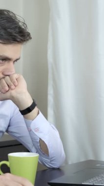 Uzaktan çalışan genç bir adamın çalışma saatleri, evdeki masa başı işçisinin çalışma ortamı, gömlekli bir çalışanın beyaz arka planda sigara içmesi.