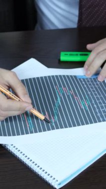 Tezgahtar kağıtlardaki grafiği yorumluyor, esnaf çalışma masasında istatistiksel belgeyi inceliyor.