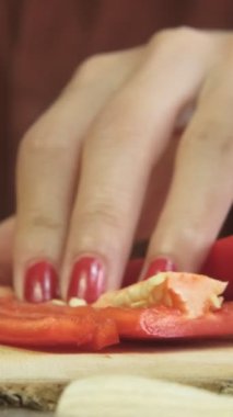 Close-up image of chopping red capia peppers, slicing process on wooden presentation plate, Julienne vegetables on the wooden presentation board, preparing thematic natural products