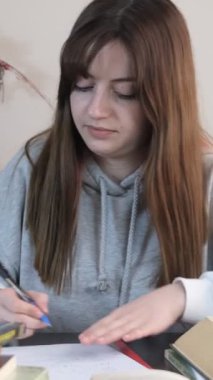 Masasında yoğun bir şekilde ders çalışan, kitap ve kalemlerden oluşan ödevlerini yapan, sınavlara sıkı hazırlanan bir kız resmi