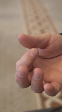 Parmaklarıyla tespih çeken yaşlı bir adam, Tasbih kullanan bir Müslüman, caminin içinde dua eden bir adamın görüntüsü.