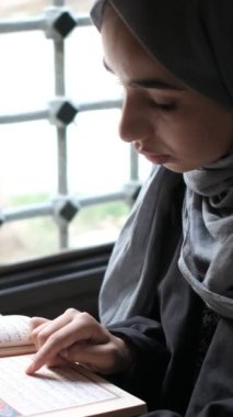 Camide ibadet, Kuran okuyan Müslüman kadın, pencere kenarında Kuran okuyan tesettürlü kız, İslam kurallarına göre dua eden.