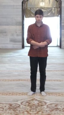 Genç Müslüman adam büyük caminin içinde ibadet eder, ibadet kurallarına göre secde eder, dini İslam 'a tapınma kurallarına göre yaşar