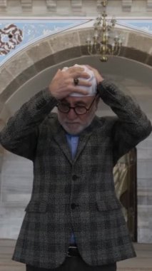 Bir de müslüman olarak, üzerinde beyaz başlık bulunan ve Kur 'an' ın âyetleri yazılı bir mescid ziyaret eden adam var. Rahman ve Rahim Allah 'ın adıyla (başlamakta) dır.