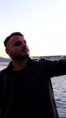 İstanbul Boğazı ile fotoğraf çektirmek isteyen genç adam temalı bir görüntü.