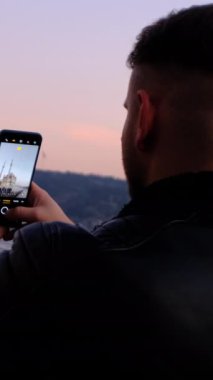 İki tarafı birbirine bağlayan Boğaz 'da manzara fotoğrafları çeken turist, feribotun görüntüsünü kaydeden genç adam, Boğaz ve gün batımını.