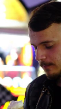 Arkasındaki kalabalık sokaktan lezzetli dondurmalar alan genç adam, turistik bir sokaktan dondurma yiyen genç adam.