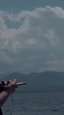 Genç adam denizde yalnız başına bir ağaca yaslanıyor ve kulaklıkla müzik dinliyor, plajda dikilen adamın arka görüntüsü...