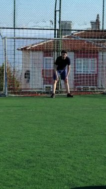 Halıda top oynayan gençlerden biri kaleciyi vuruyor. Kaleciye penaltı sahasından top atan adam.