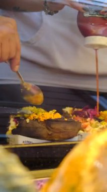 Kumpir tezgahının arkasında kumpir yapmak, fırında patatese çeşitli soslar ve aperatifler ekleyerek servis edilen bir sokak lezzeti.