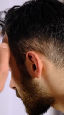 Saç dökülmesini kontrol eden adam, saç dökülmesini dert eden konsept görüntü, aynanın önünde cildini kontrol eden adam.